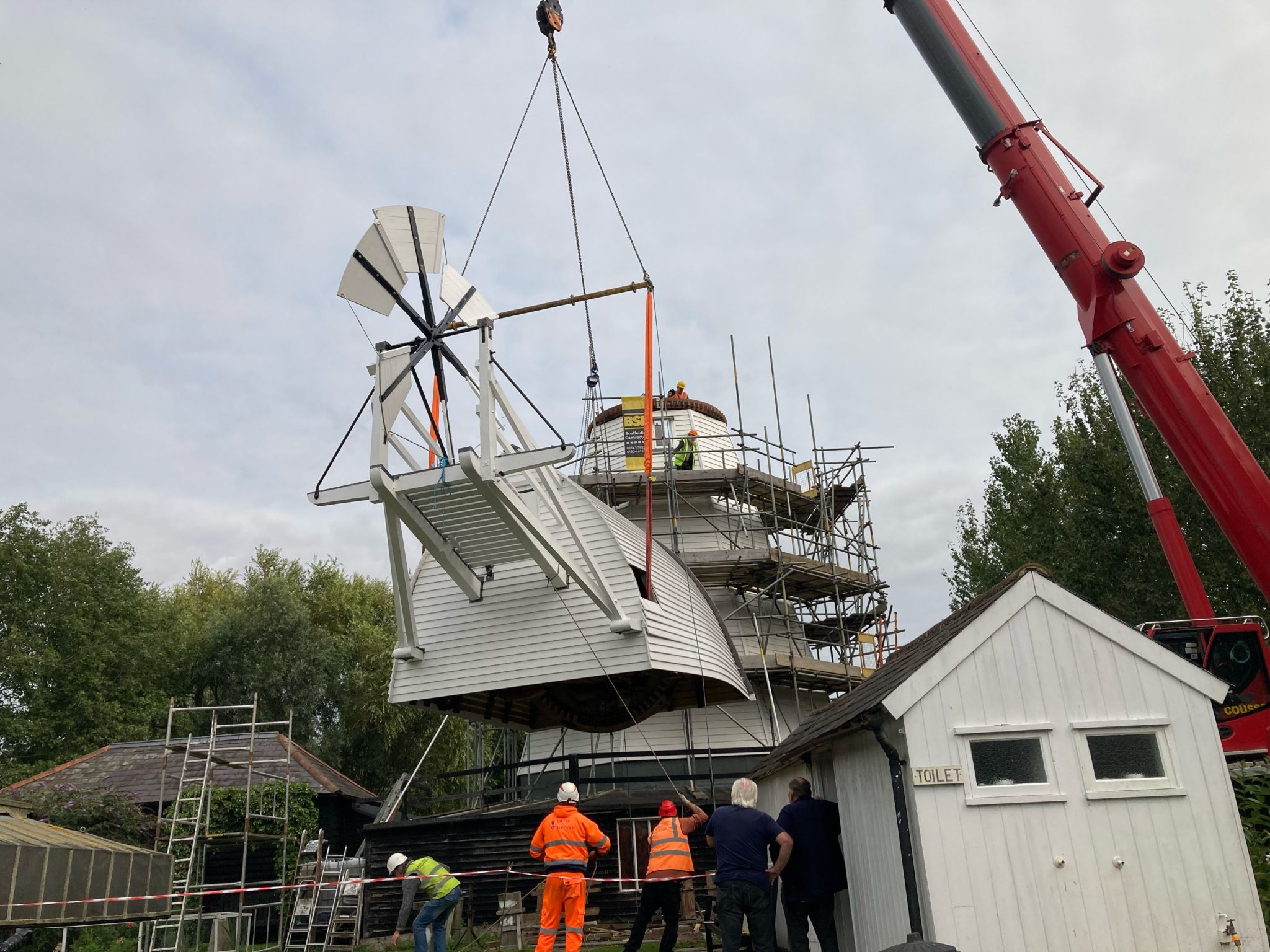 A crane lifts the 18th Century windmill cap into position