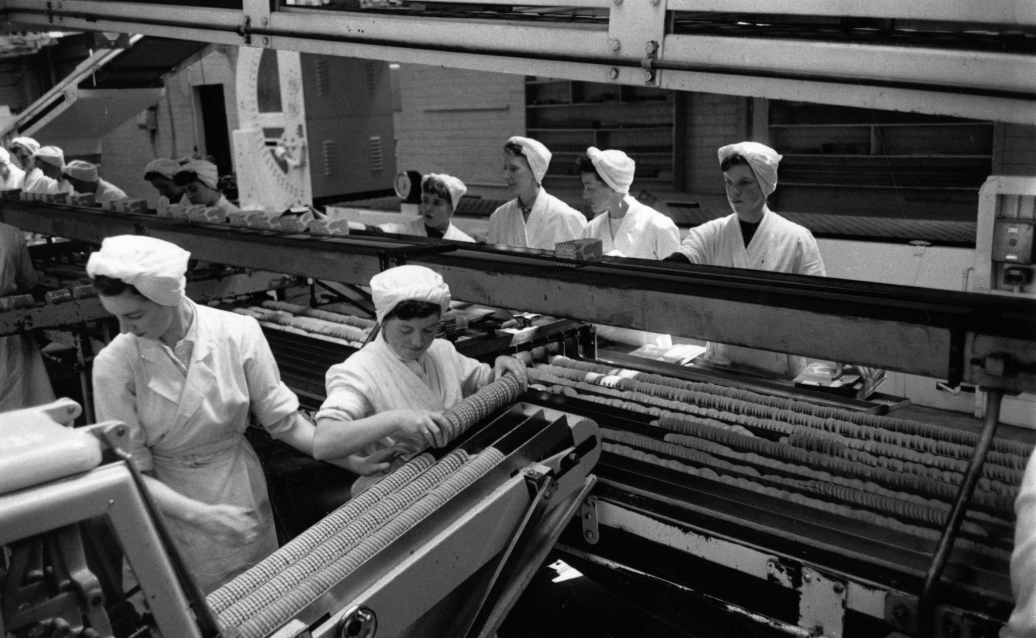 20th August 1955: Workers checking the quality of biscuits on a conveyor belt in the Glengarry Bakery of William Macdonald and Sons, Glasgow. This company's 24-hour production line generates a constant stream of biscuits and produces a quarter of Britain's total chocolate biscuit output. Original Publication: Picture Post - 7942 - Let Glasgow Flourish! - pub. 1955 (Photo by Haywood Magee/Picture Post/Hulton Archive/Getty Images)