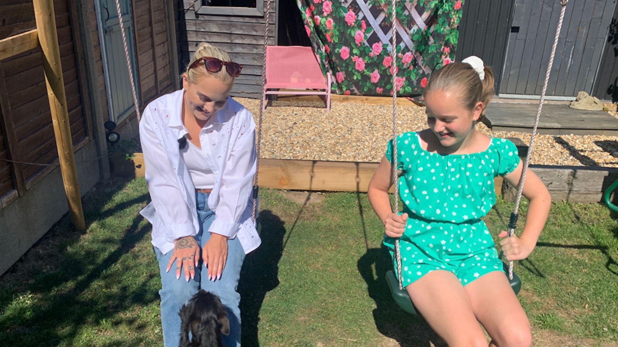 Annalise and her mum Kasey sitting on swings in a garden.