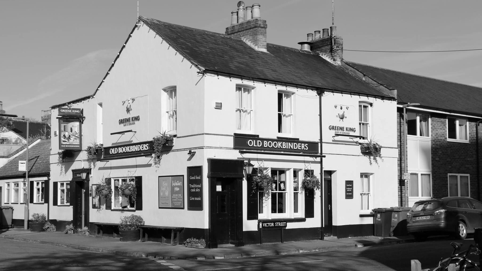 The Old Bookbinders pub on a quiet Victor Street, with signs saying it offers good food, traditional cask ales and live music. This image is in black and white