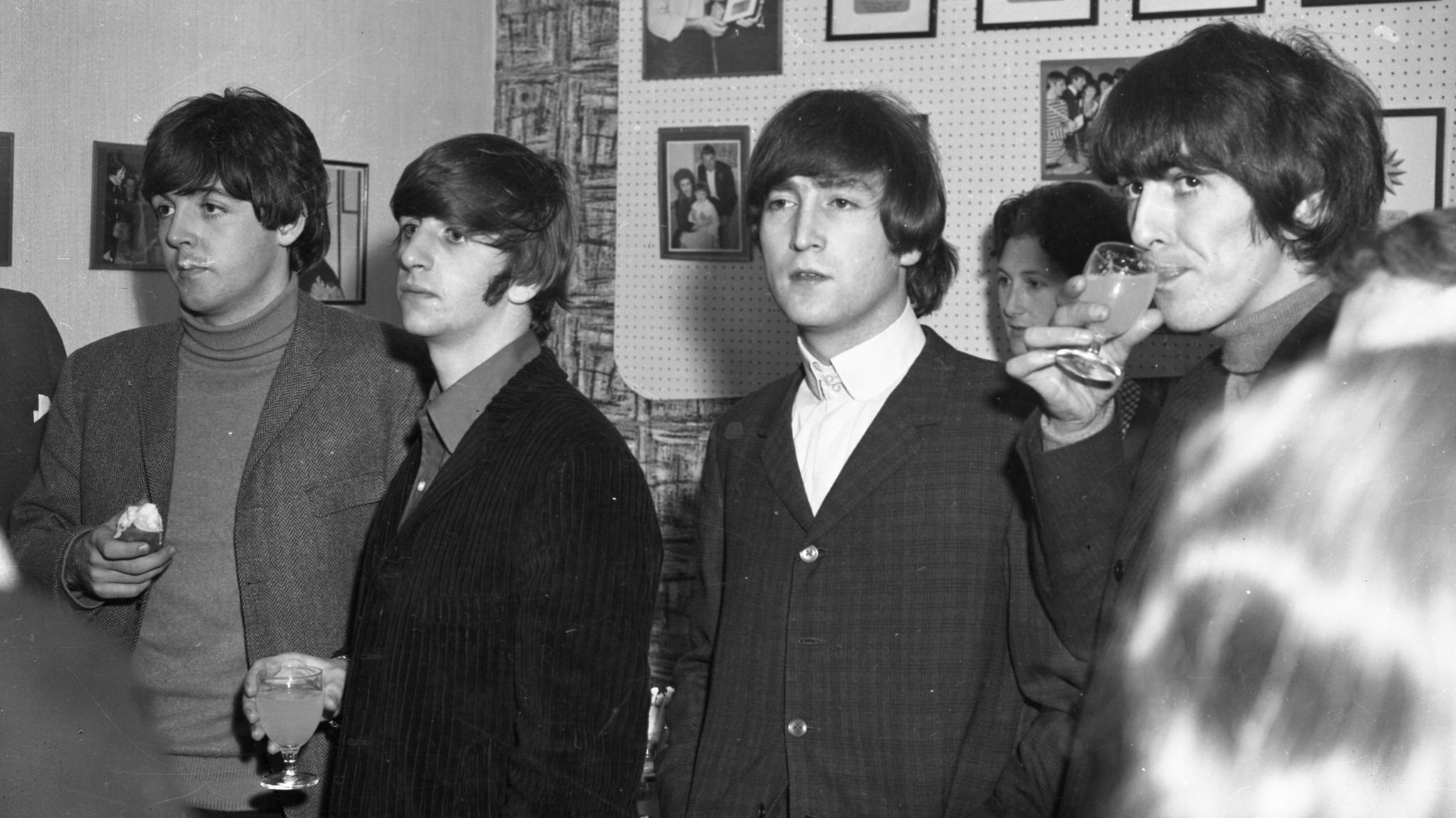 The Beatles standing with drinks in a room at the Ipswich Gaumont theatre in 1964