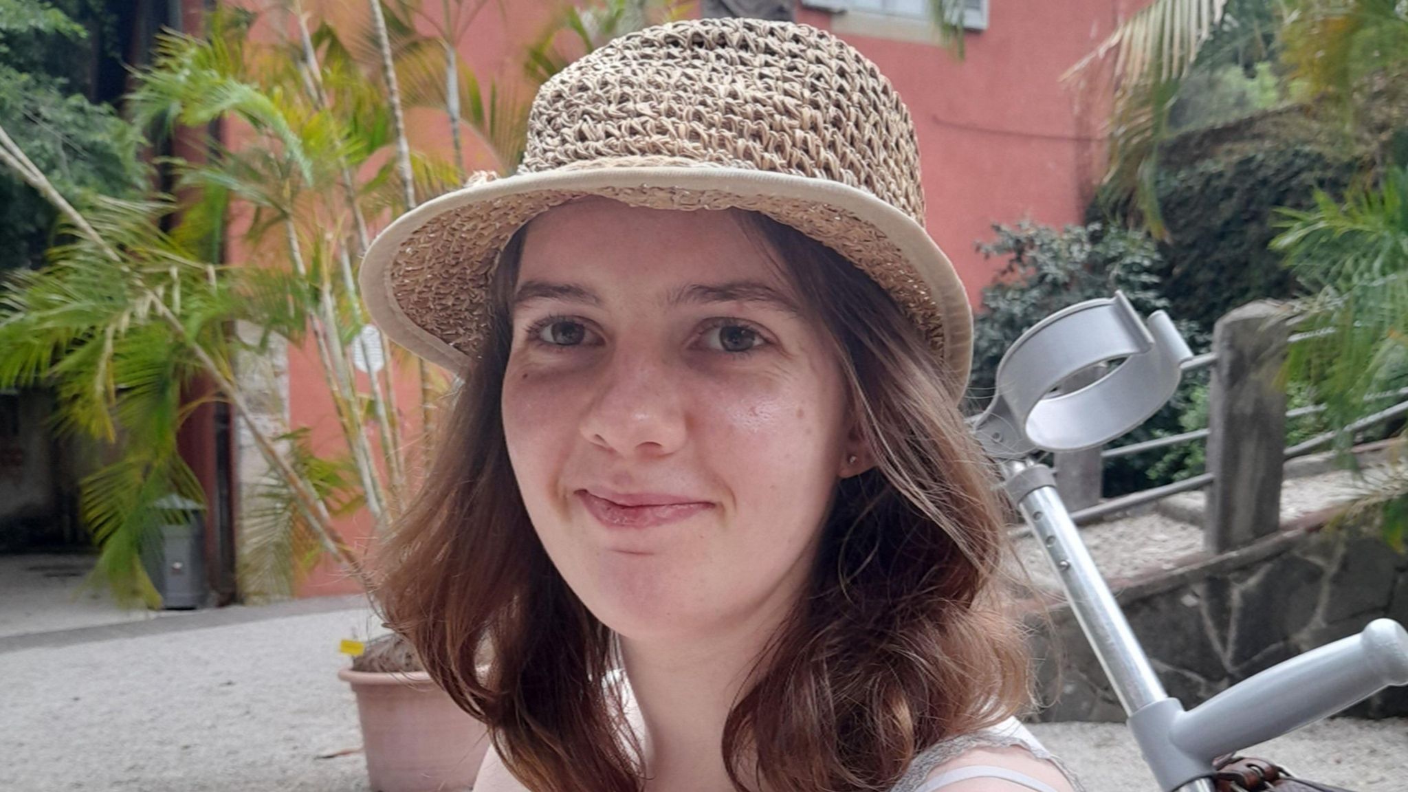 Poppy Garton wearing a summer hat. Poppy has shoulder-length brown hair and is smiling at the camera.