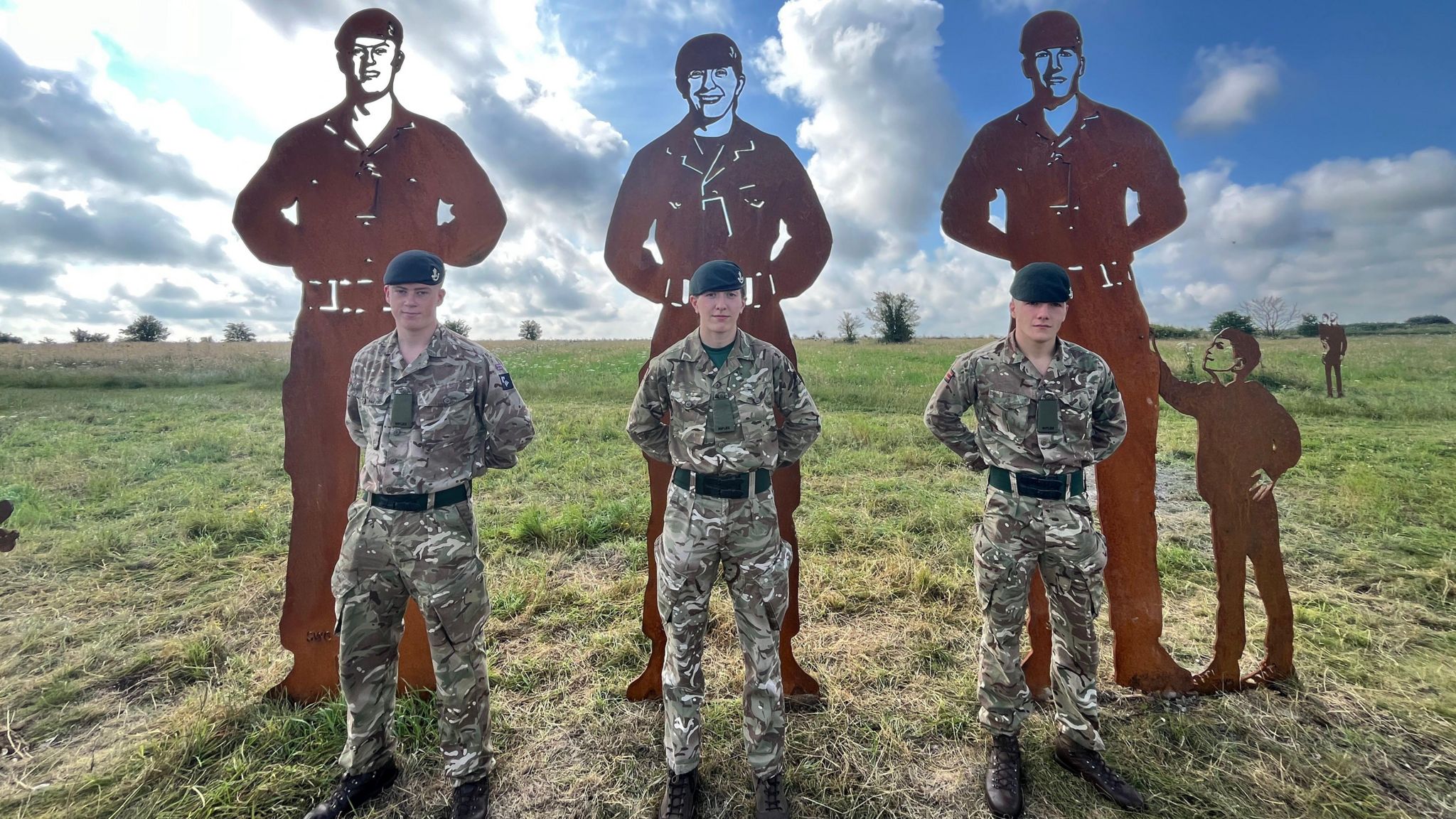 Soldiers standing in front of the statues they inspired