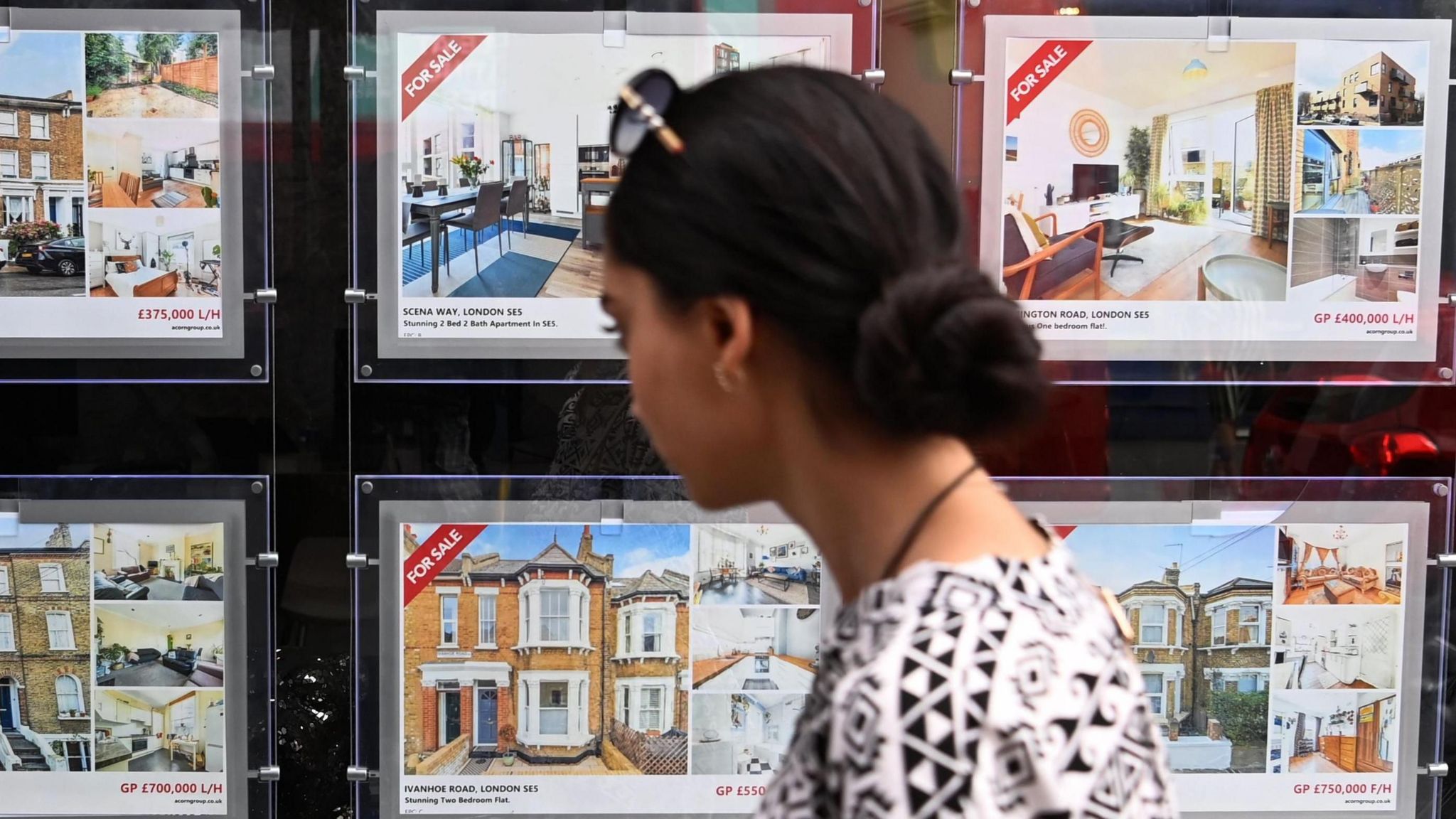 A woman looks at house for sale signs in an estate agents window