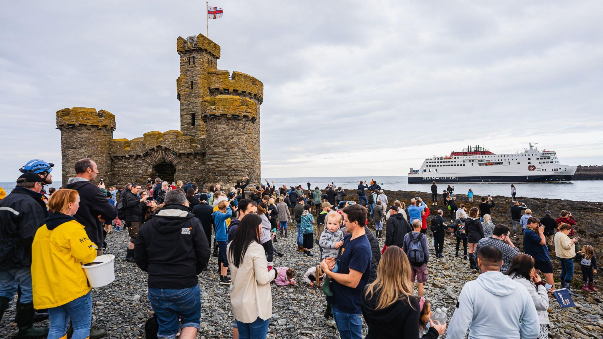 Crowds on the island with a tower with the ferry in the background