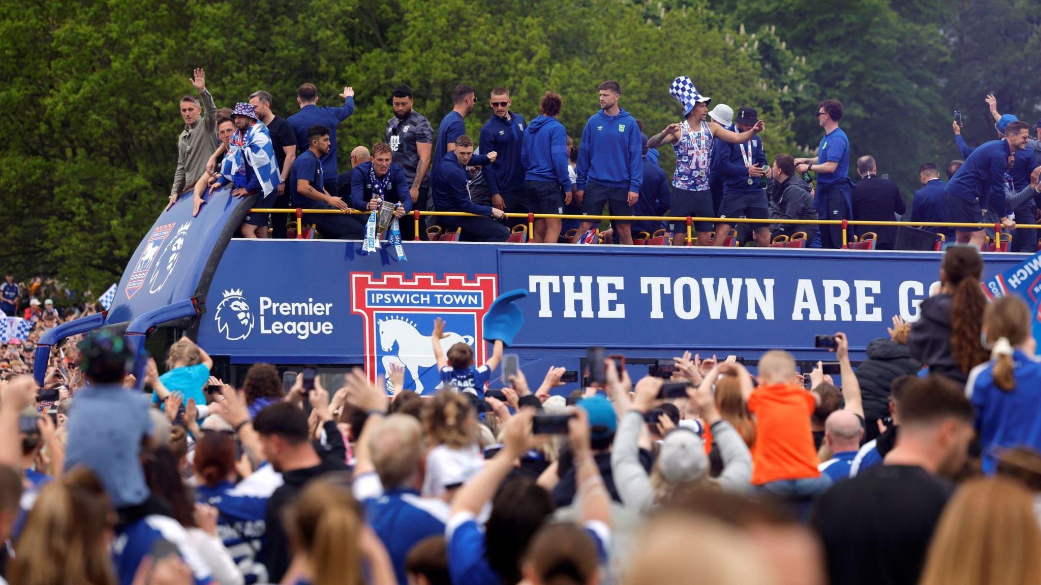 Fans greet Ipswich Town players, who are stood atop a blue victory bus