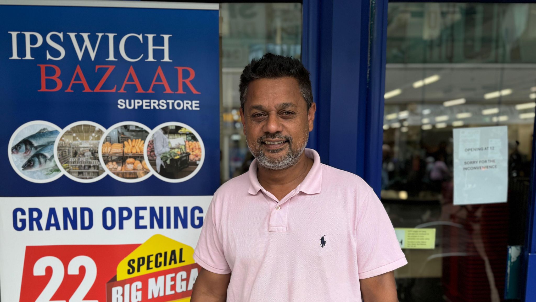 Ariful Islam, in a white polo shirt, smiles as he stands outside his new store