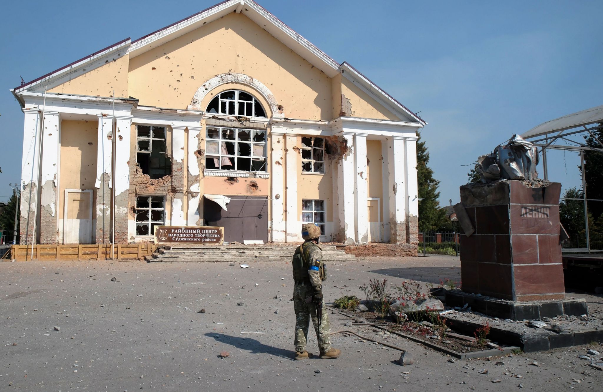 A Ukrainian serviceman stands near a damaged building in the Kursk region 