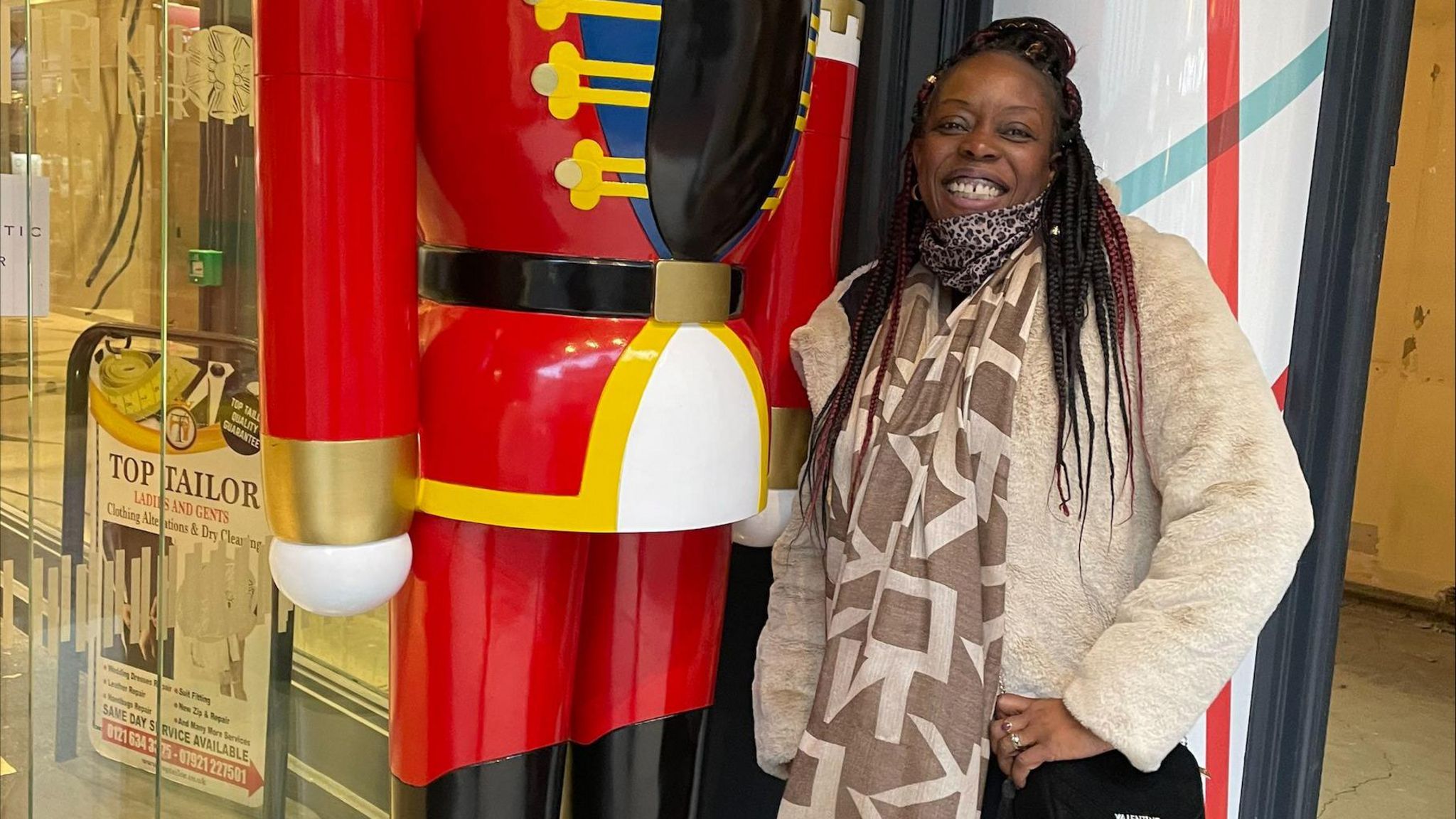 Jessica Bonner out and about. She is posing next to a statue and is smiling. She is wearing a large scarf and a warm jacket. 