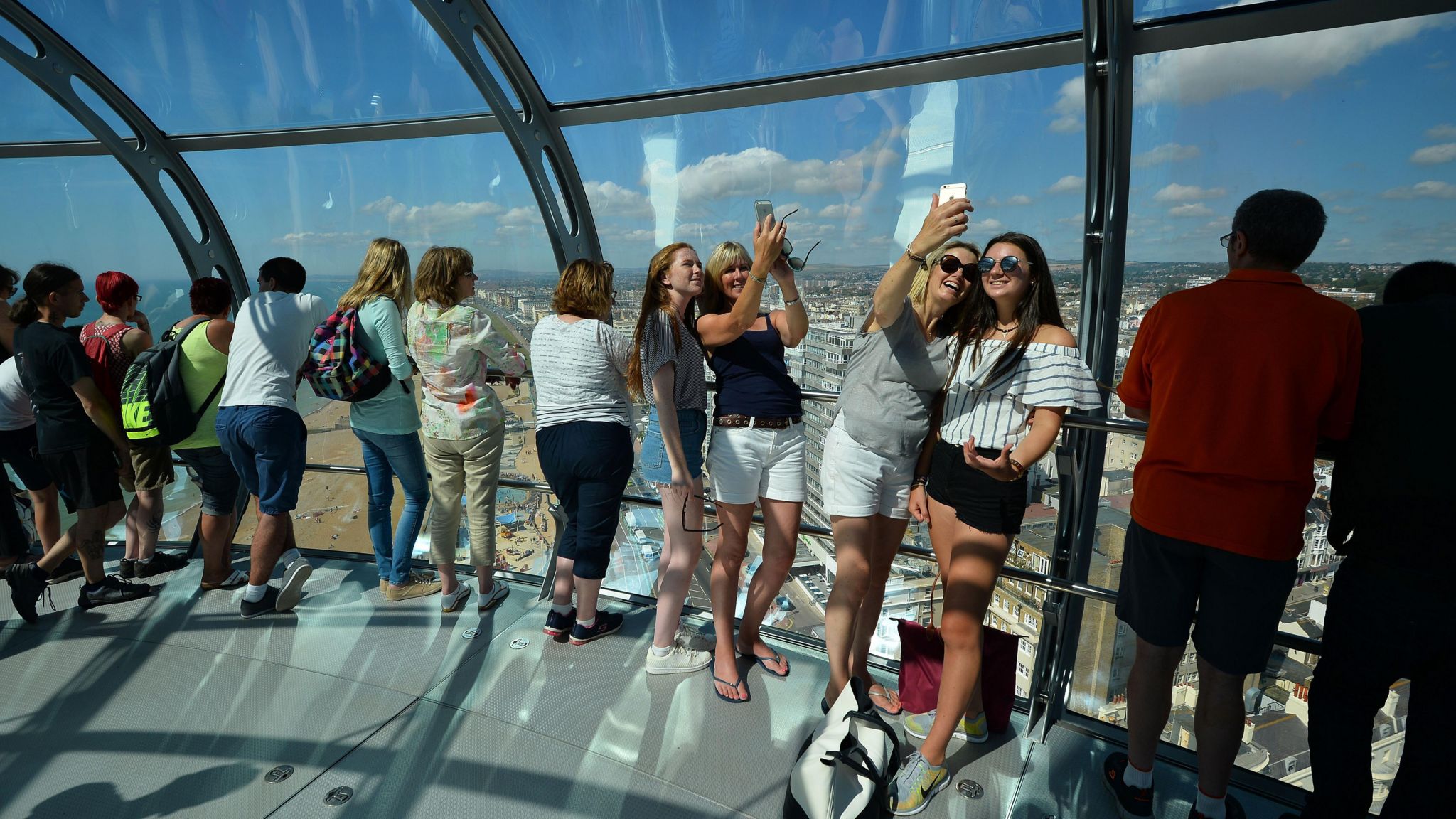 Visitors smile, look at the view and take pictures in Brighton's i360 tower