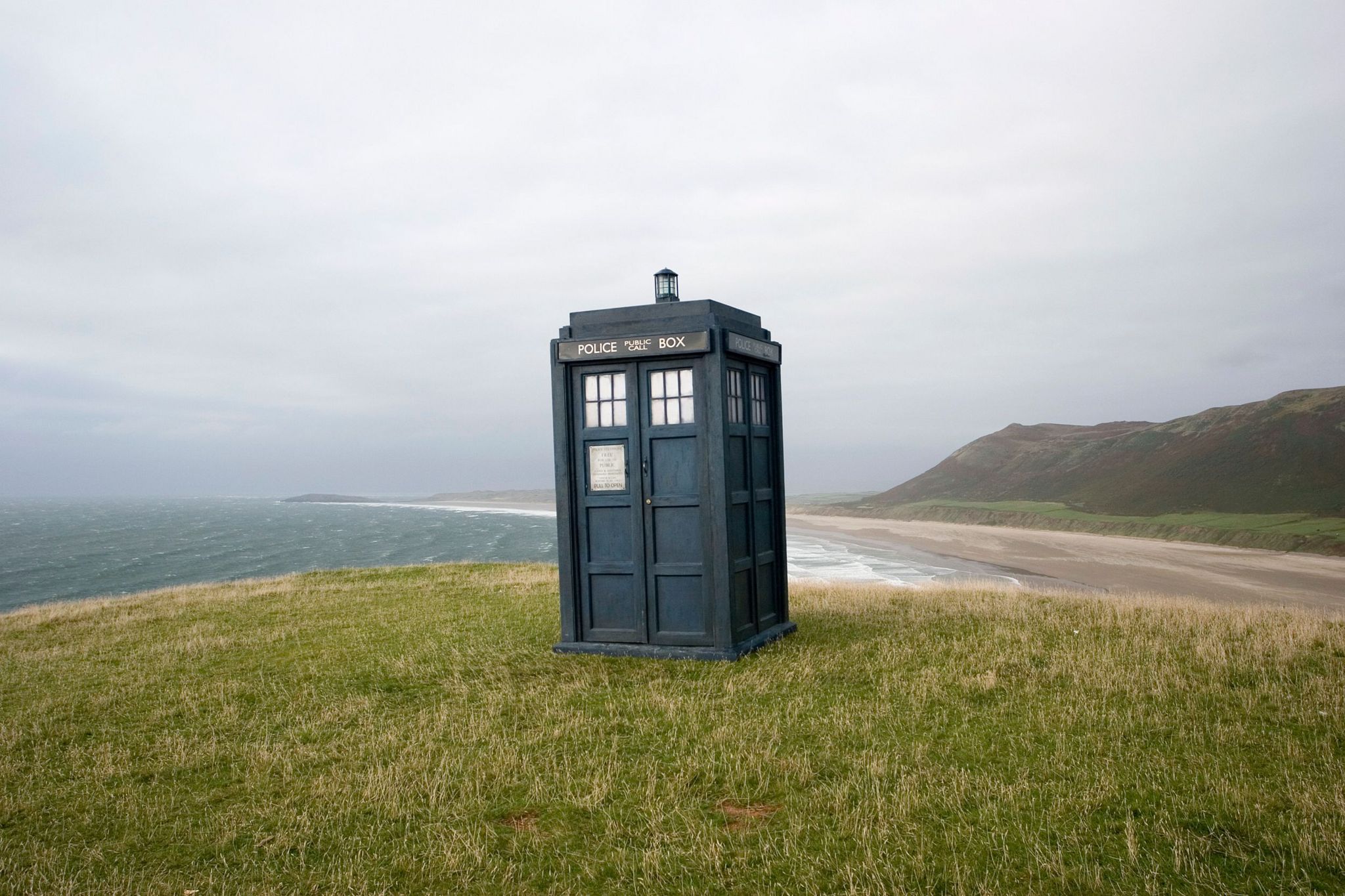 The TARDIS on a grassy hill overlooking the sea