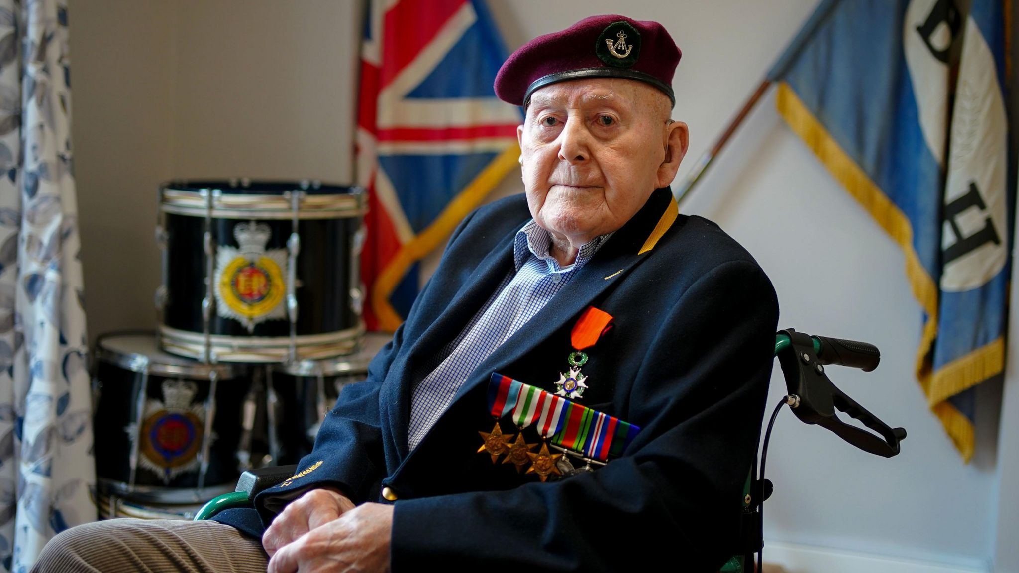 D-Day Veteran Peter Belcher with his medals in front of military flags and drums