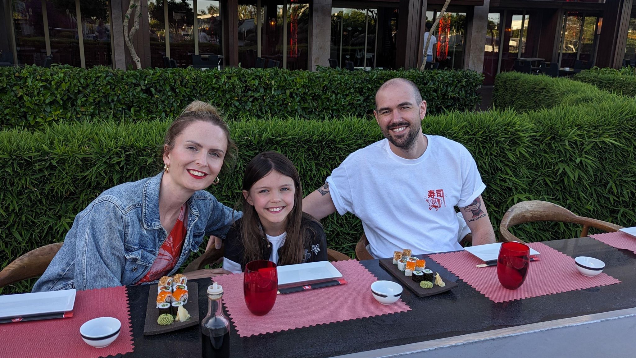 Emma, sitting in a restaurant with plates of sushi on the table, with her husband Dan and their nine-year-old daughter in the middle