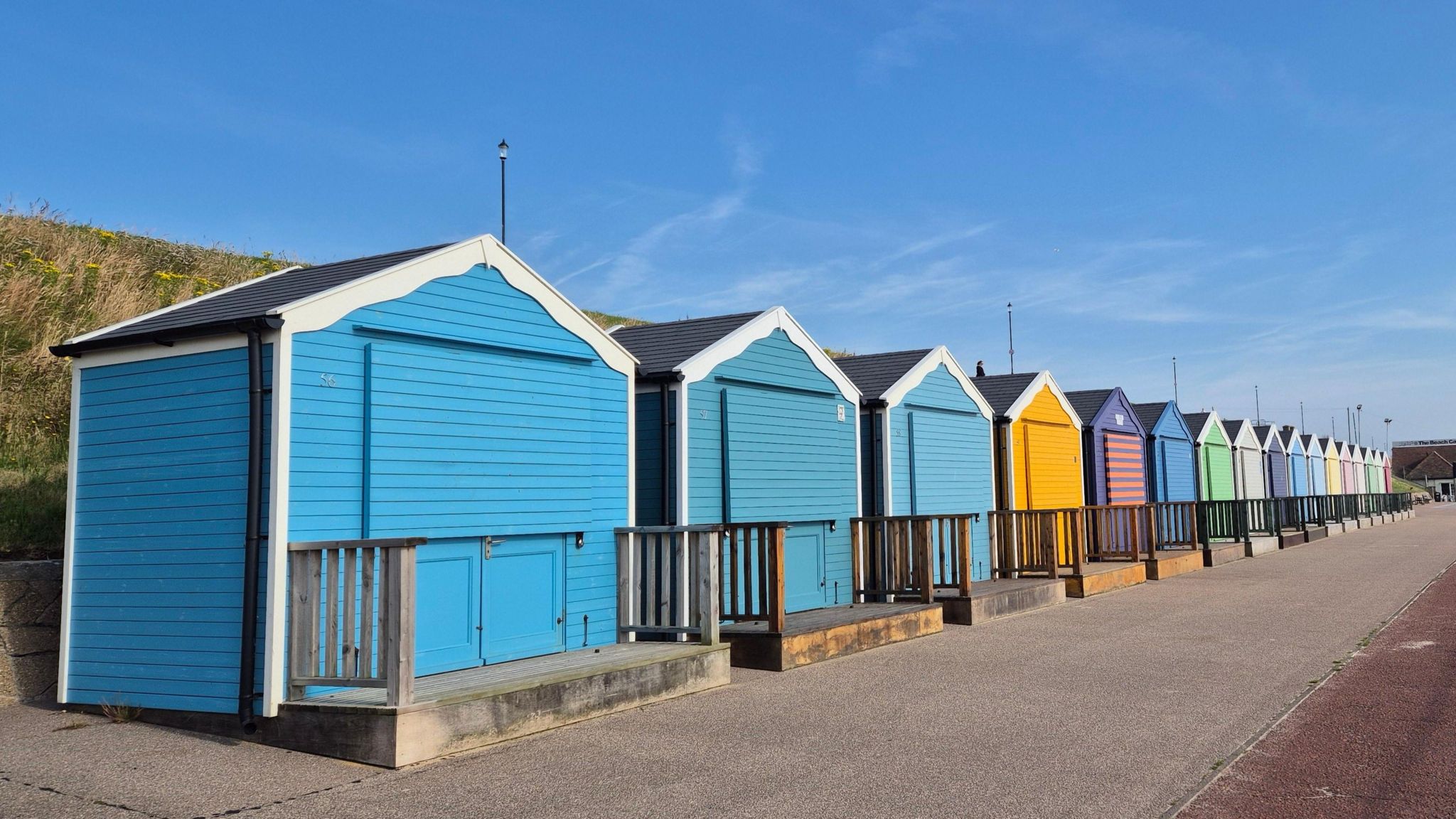 A row of colourful beach huts beneath a blue sky