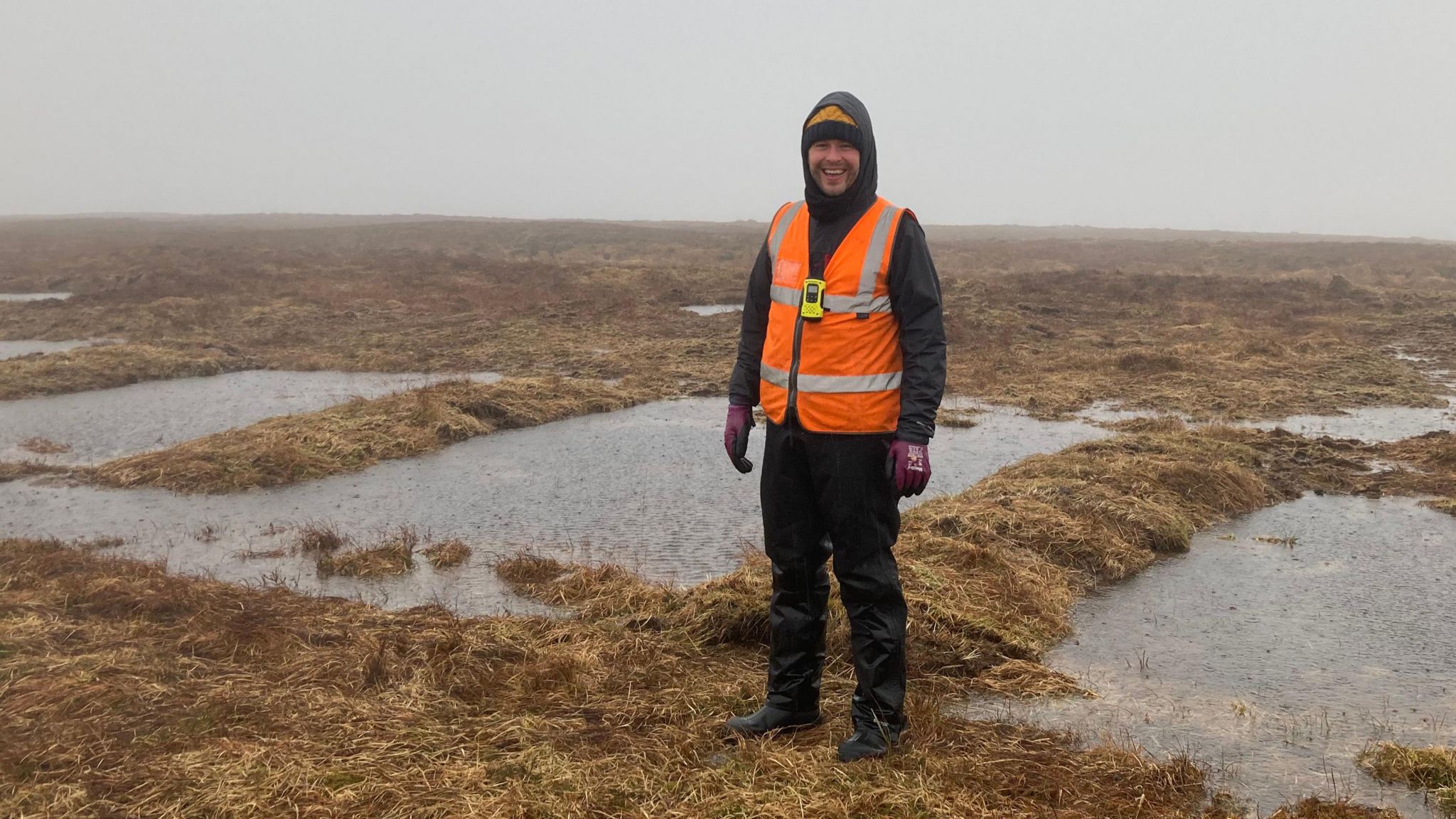 Project officer standing in front of pools created by teh peat restoration works.