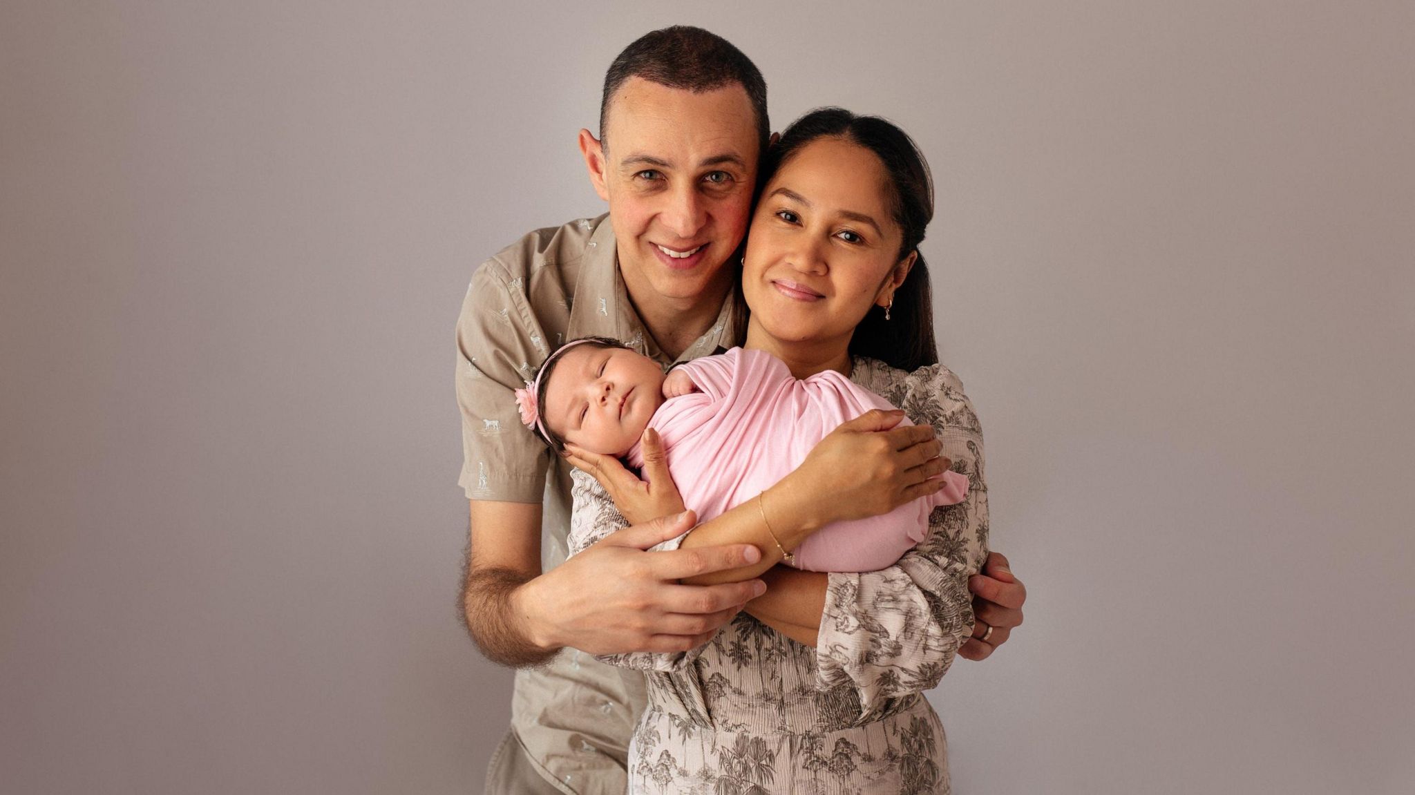 Bella in a pink blanket, being held by her parents