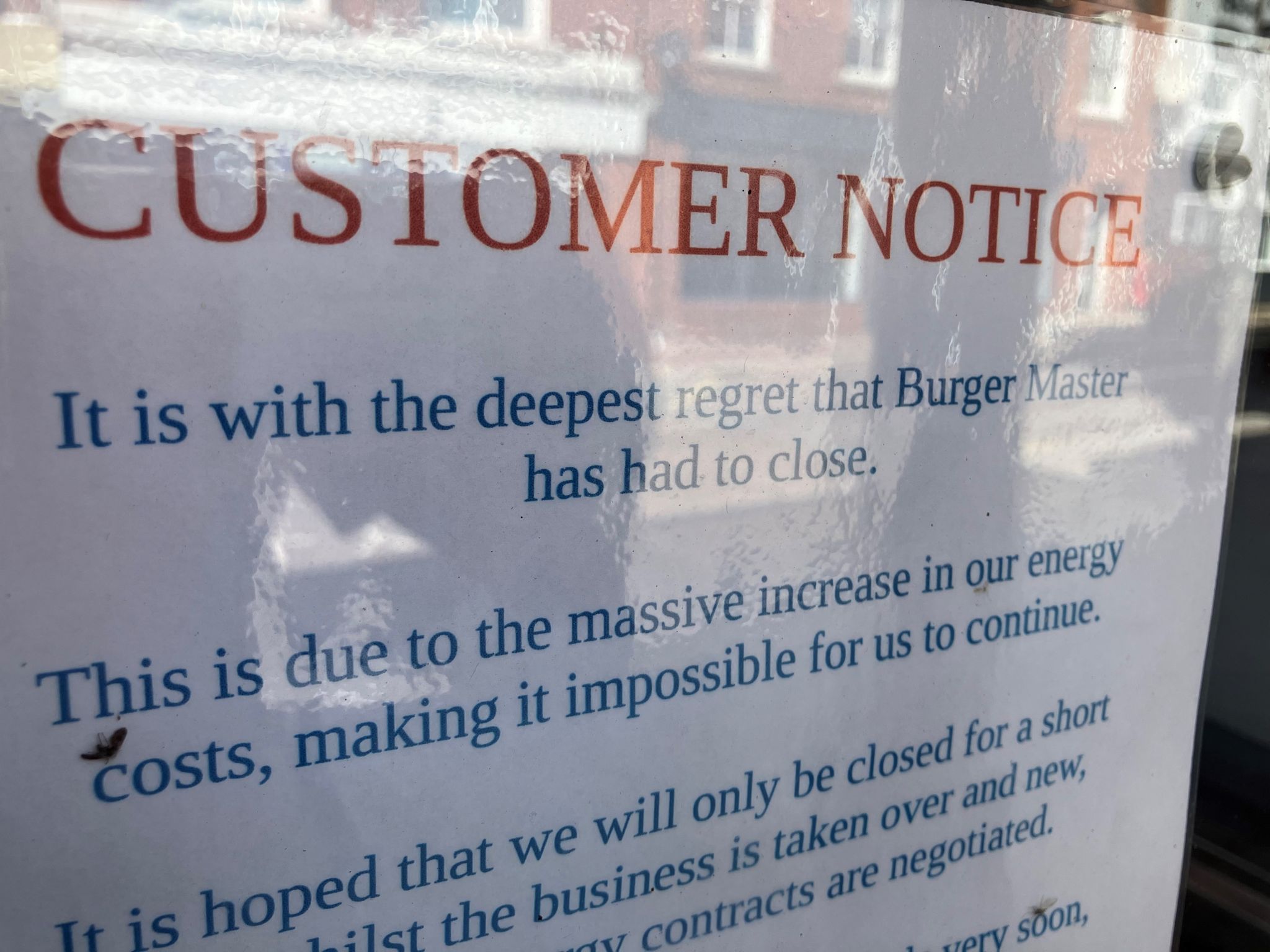 A sign on the door of a burger shop says it has closed because of energy costs