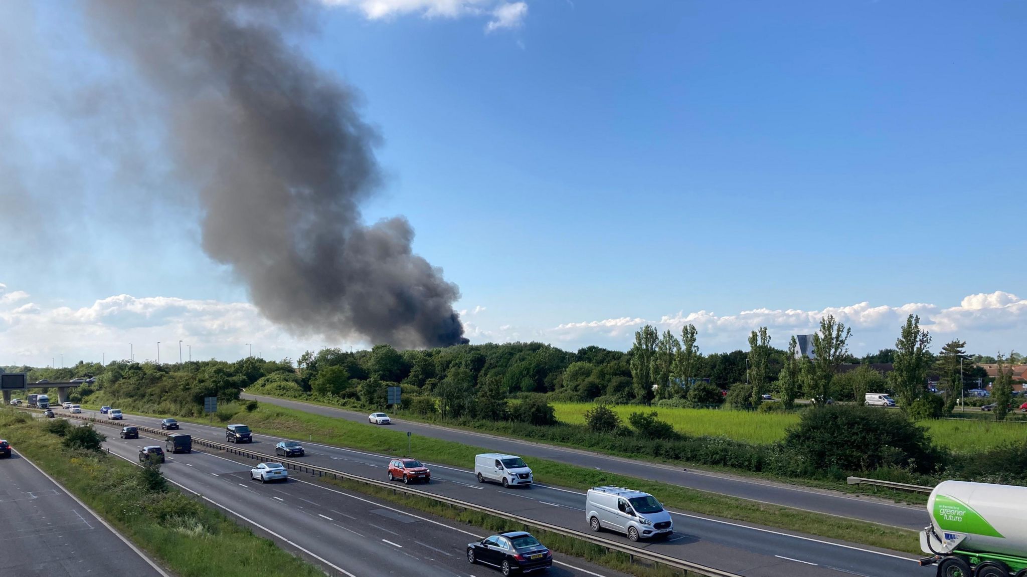 Large plume of black smoke rising above trees on the edge of the A14 near Milton, Cambridgeshire