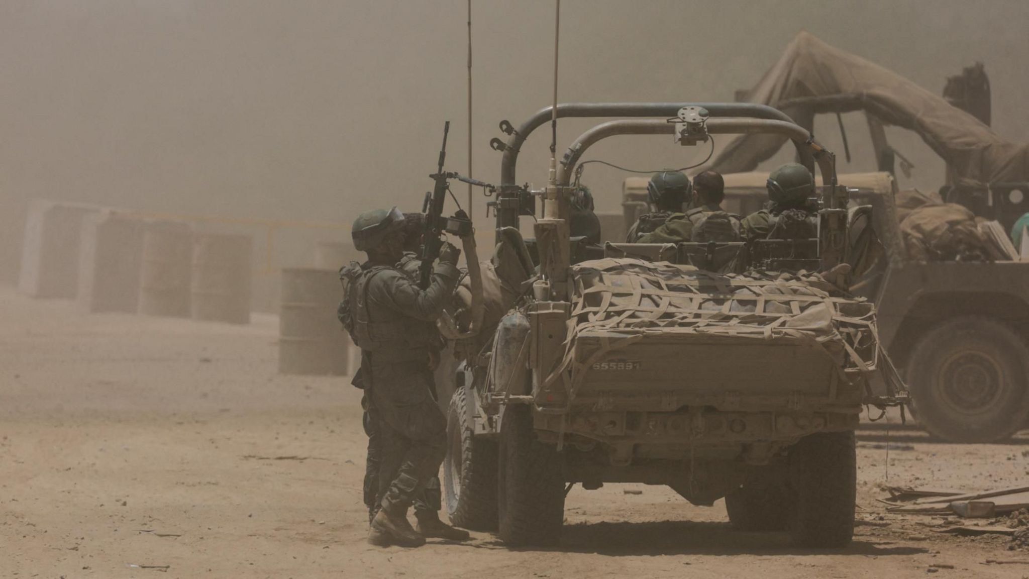 Israeli soldiers stand next to a military vehicle, near the Israel-Gaza border (2 July 2024)