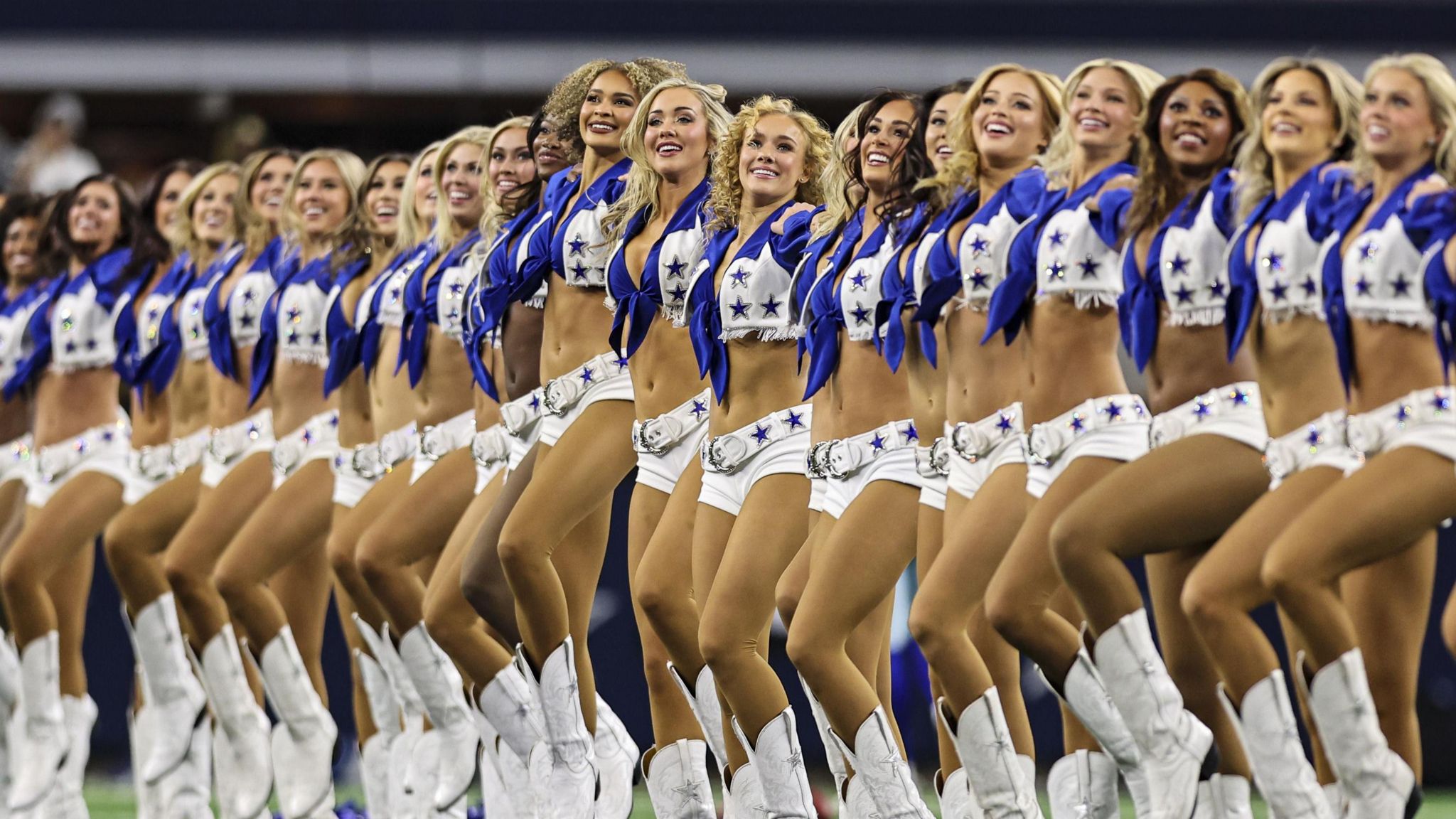 Smiling members of the Dallas Cowboys Cheerleaders standing in their uniforms in a row