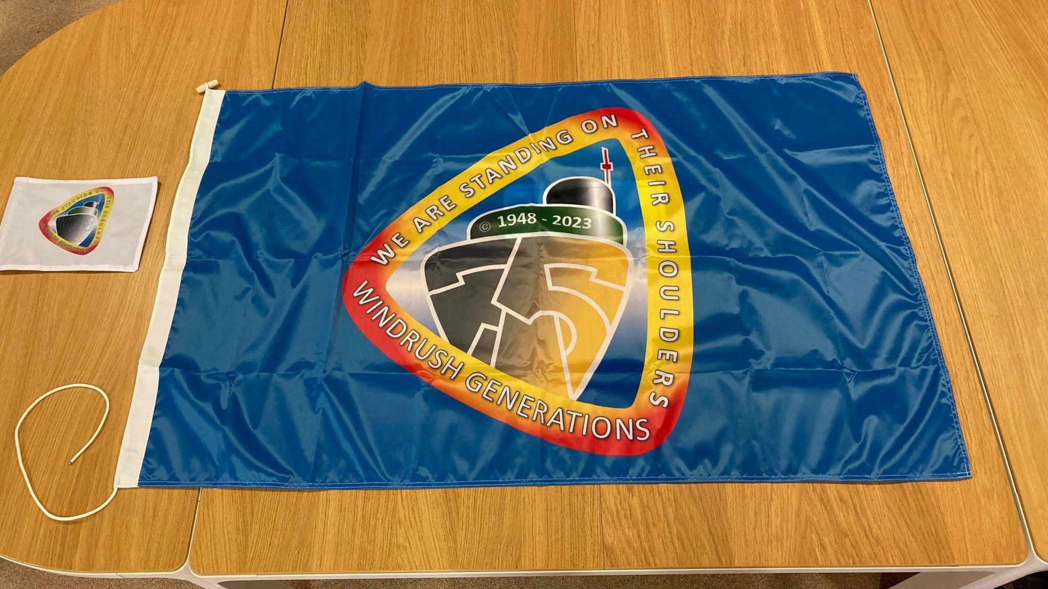 The multicoloured Windrush Generations flag laid out on a table 