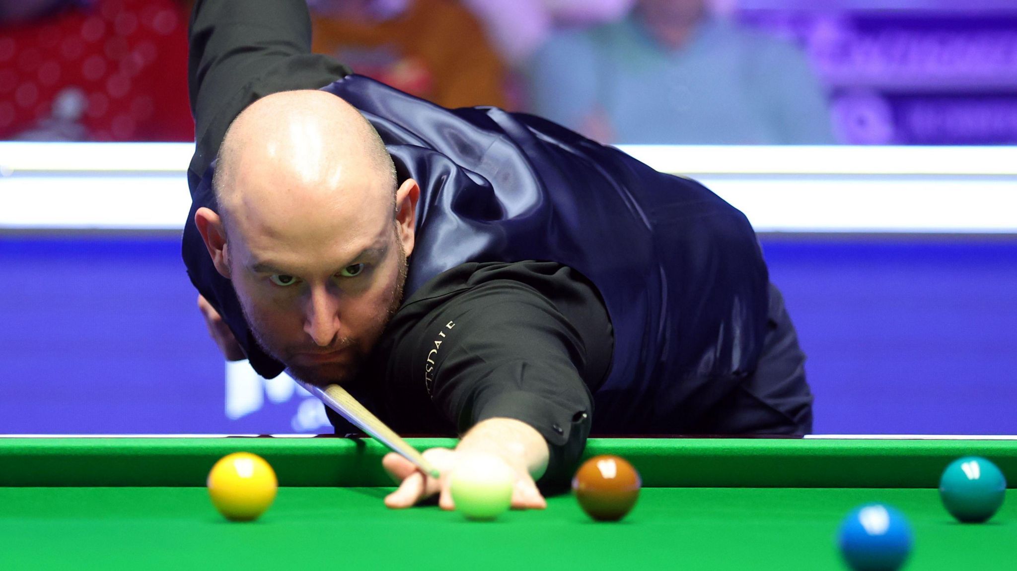 Matthew Selt playing snooker. He is leaning on the table and looking down his cue as he prepares to strike a ball.