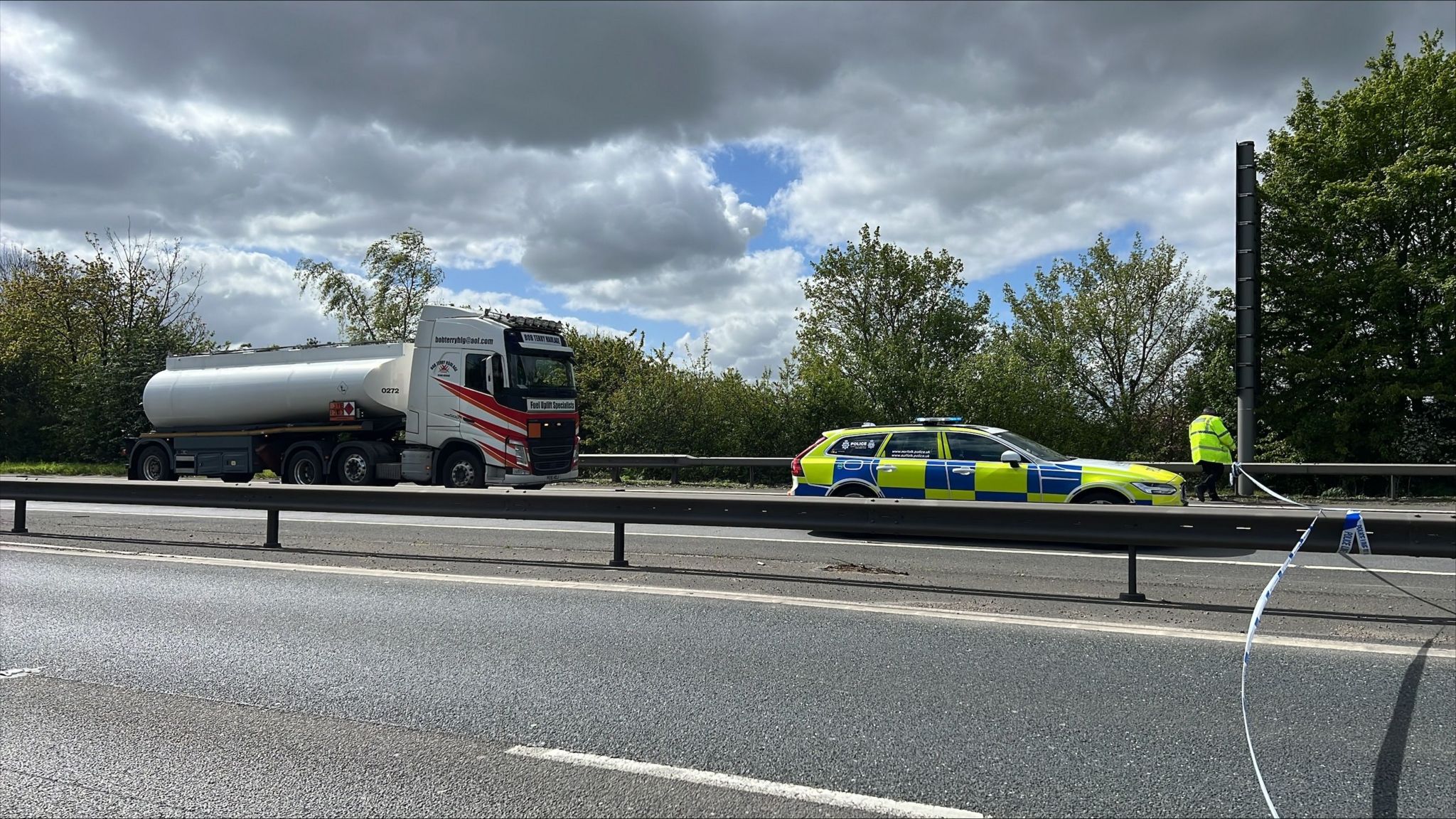 A lorry and a police car on the A12 northbound. There is a police officer and a police cordon put in place over the road
