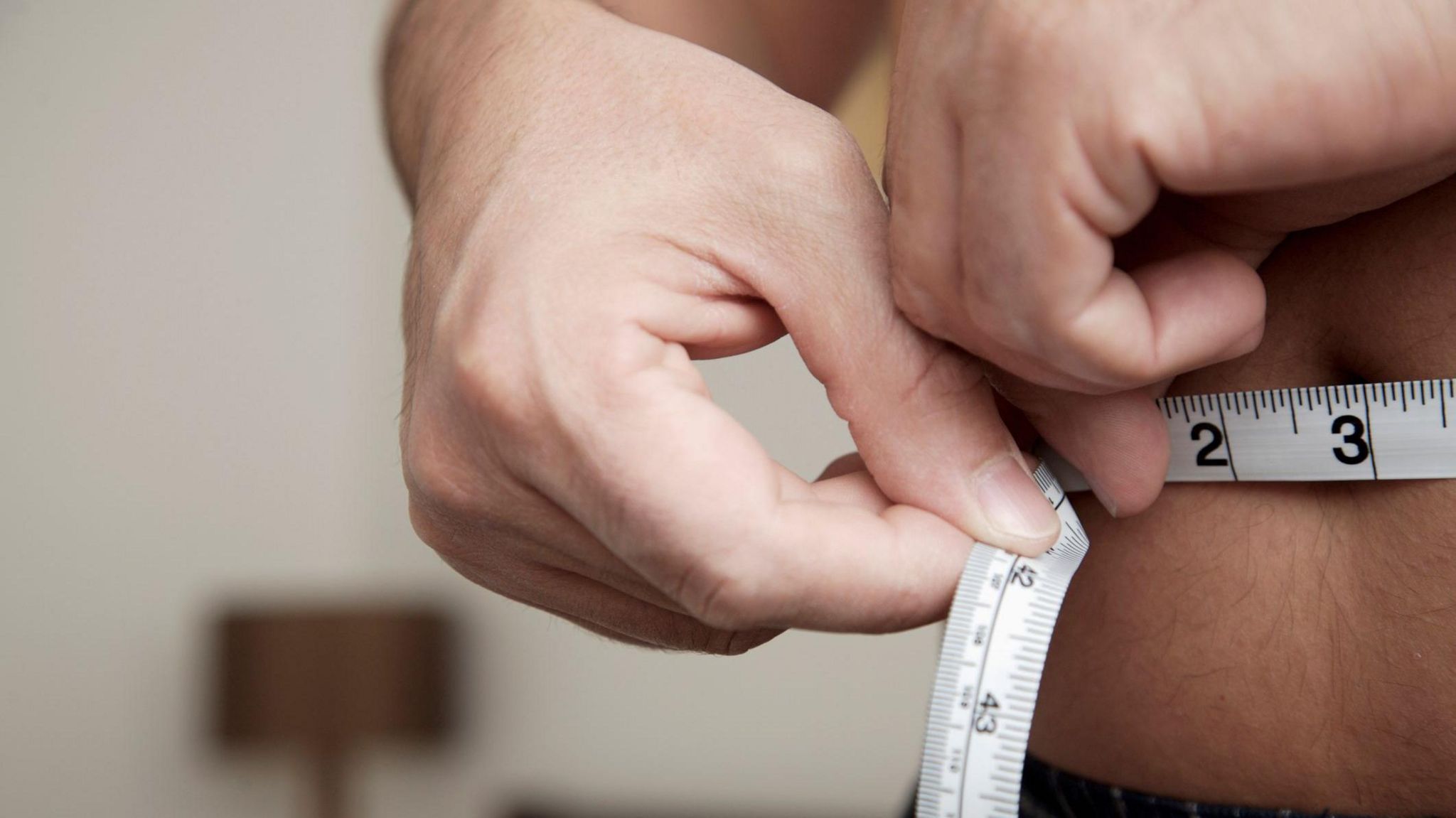 A tape measure being held around a person's waist