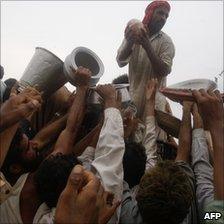 Pakistani flood victims crowd around supplies of food relief