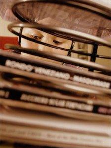 Boy listening to music behind stack of CDs
