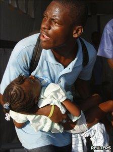 A man carries a child with symptoms of cholera to receive treatment in a clinic set up by International Red Cross in Port-au-Prince (24 November 2010)