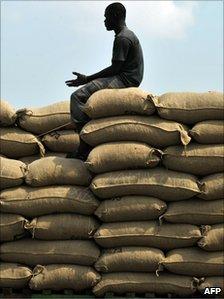 A man stands next on cocoa bags in front of a warehouse at the Abidjan port on December 9, 2010