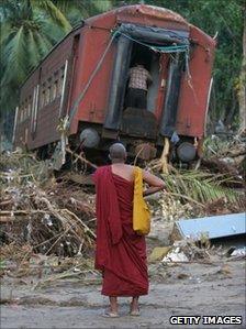 Buddhist monk looks at a wrecked train carriage 30 December 2004 near Galle, Sri Lanka