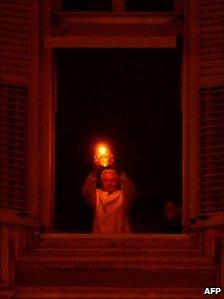 The Pope lights a nativity candle from his window