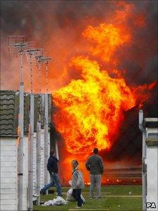 Prisoners collect their belongings as a blaze burns on 1 January.