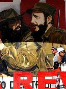 Tourists walk past a painting depicting guerrilla leader Camilo Cienfuegos and Fidel Castro in Havana on 29 December 2008