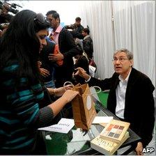 Turkish author and Nobel laureate Orhan Pamuk (R) signs books at the Jaipur Literature Festival, India, 21 January 2011
