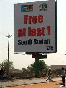 Southern Sudanese walk under a billboard in Juba on 7 February 2011, which celebrates the choice of the south to separate from the north
