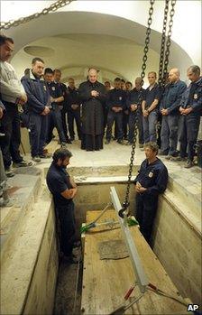 Workers pause for prayers before removing Pope John Paul II's coffin from its crypt in St Peter's Basilica, the Vatican, 29 April