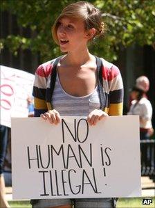 A protestor holding a sign which says "no human is illegal' in Huntsville, Alabama