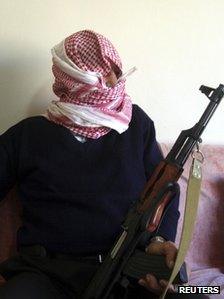 Weapons dealer Abu Wael, covering his face with an Arab keffiyeh headdress and clutching one of his rifles, speaks with Reuters, in Lebanon's Bekaa valley, November 21, 2011.