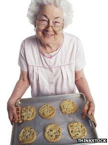 An elderly lady with a tray of biscuits