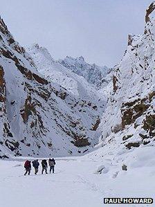 Four people walking through the Zanskar river gorge