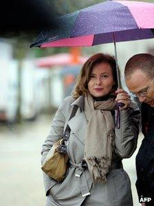 Valerie Trierweiler (L), companion of the President of the Correze Council General Assembly Francois Hollande, stands under an umbrella during a visit at the marketplace on April 21, 2012 in Tulle, southwestern France