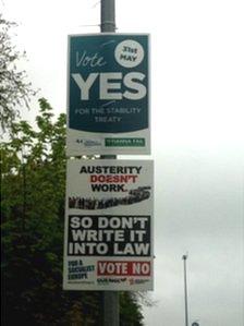 Two posters on a lamppost, one says vote yes, the other says vote no