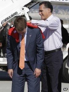 Romney signs a t-shirt on the back of his "body man" Garrett Jackson