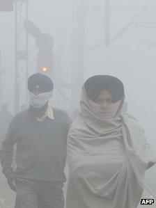 Indian passengers wait for their trains at a fog-covered railway station in Amritsar on December 24, 2012.