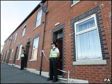 Police stand guard outside two houses on Percival Street in Blackburn