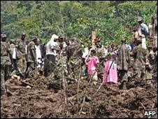 Ugandan villagers and soldiers stand on fresh earth following a landslide. Photo: 2 March 2010
