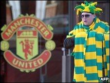 A man sells green and yellow scarves outside Old Trafford